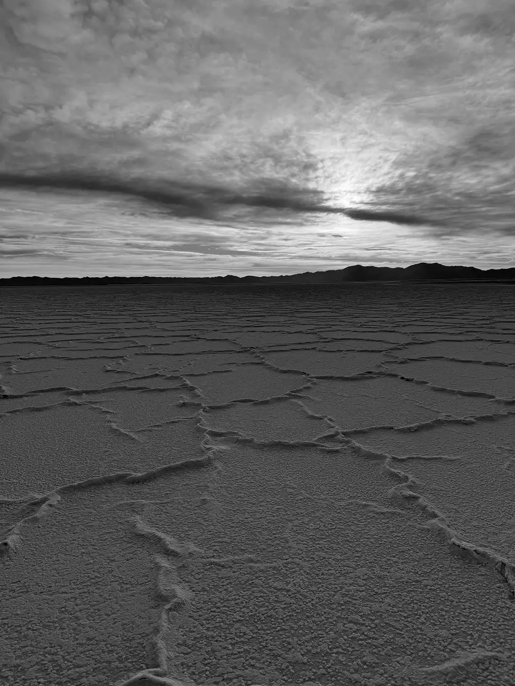 Costra de sal de un salar, con montañas en el horizonte y cielo nublado